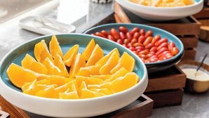 Une table de buffet avec des saladiers remplis de tranches d’orange et de haricots rouges.