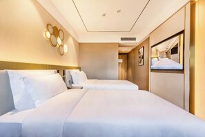 A hotel room with two beds, a large mirror, and a wall-mounted light fixture.