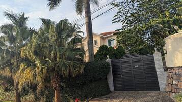 A residential property with a gated entrance, palm trees, and a well-maintained garden.