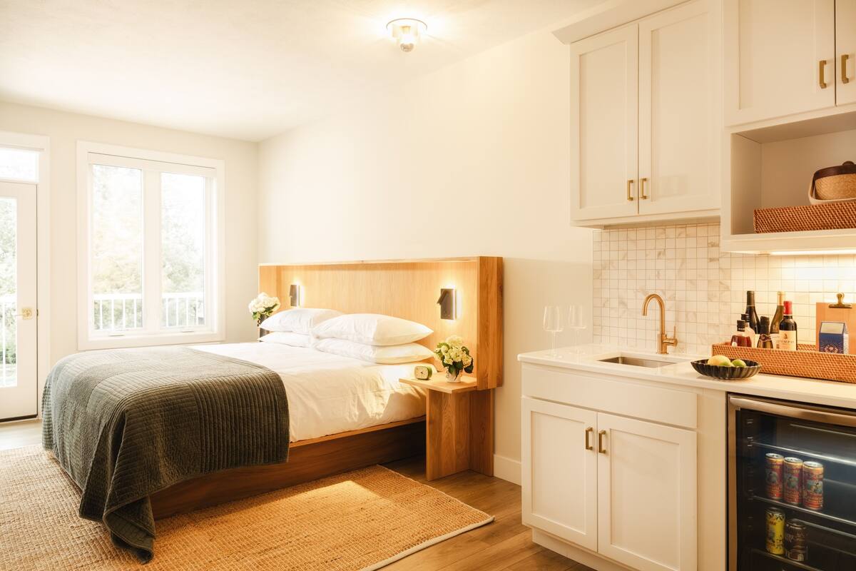 A bedroom with a bed, bedside table, and a nightstand with a lamp.