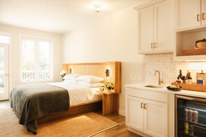 A bedroom with a bed, bedside table, and a nightstand with a lamp. - Dexter Hotel (Elk Rapids)