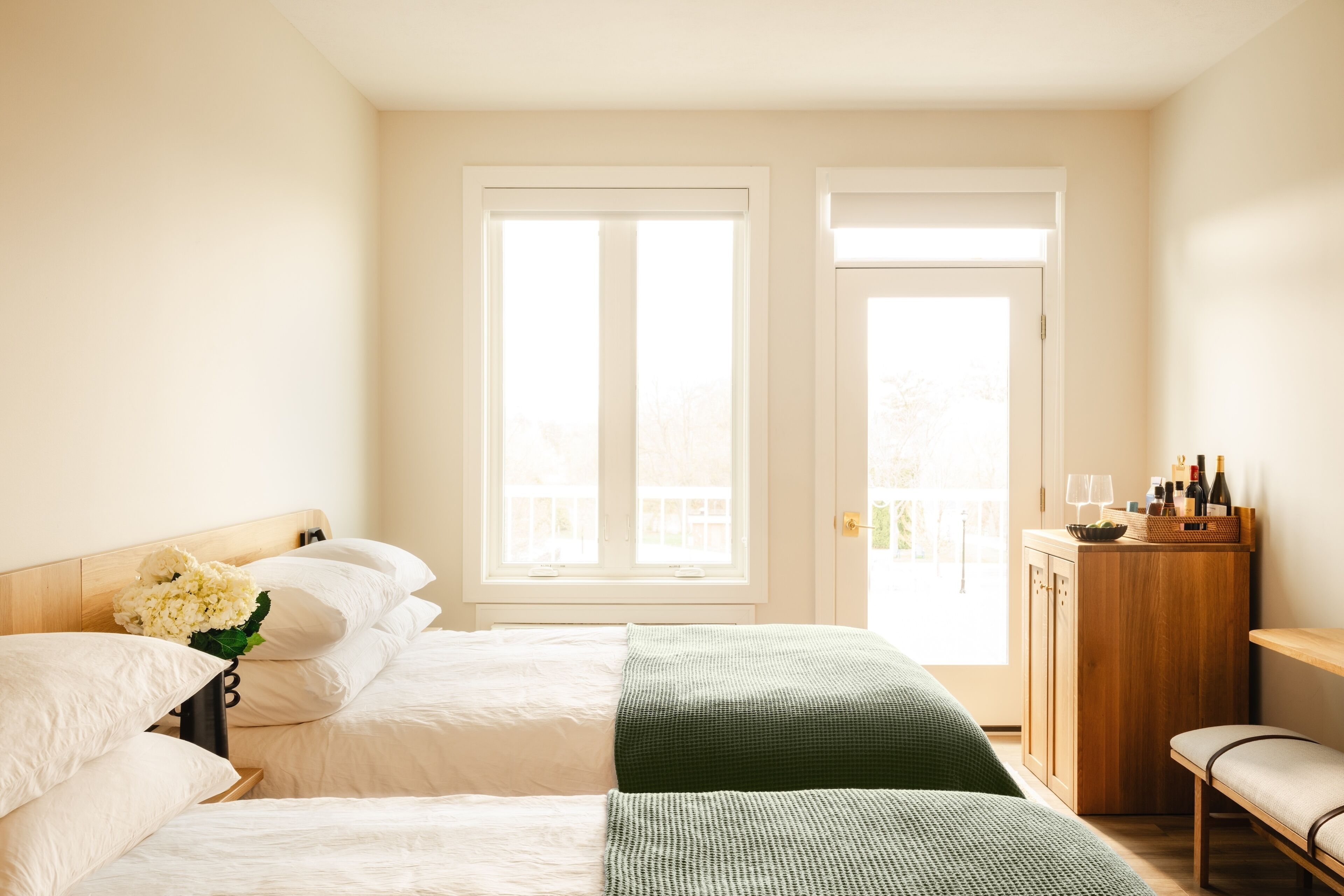 Habitación de hotel con dos camas, un armario de madera y un banco.