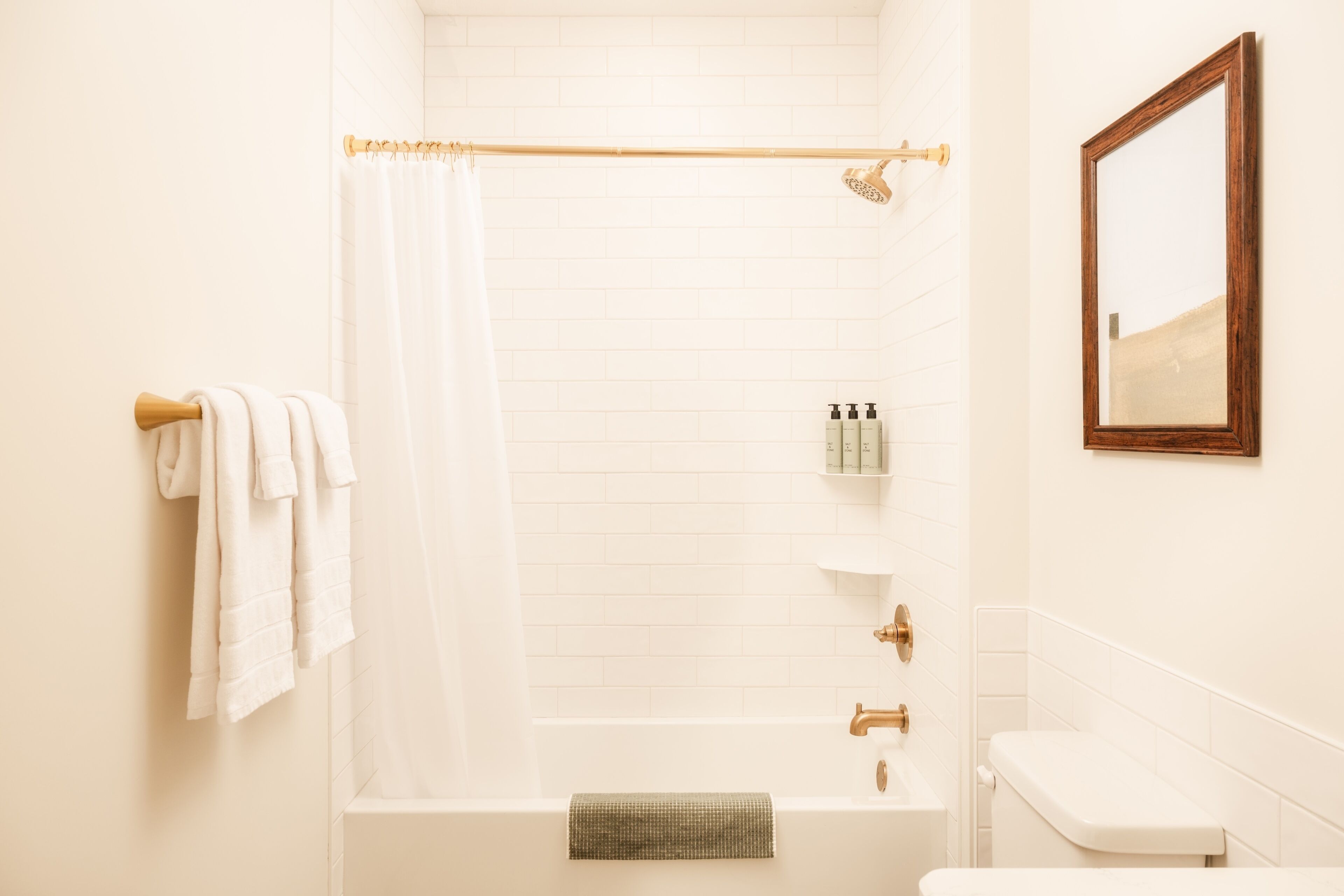 Un baño con bañera, inodoro, cortina de ducha y espejo.