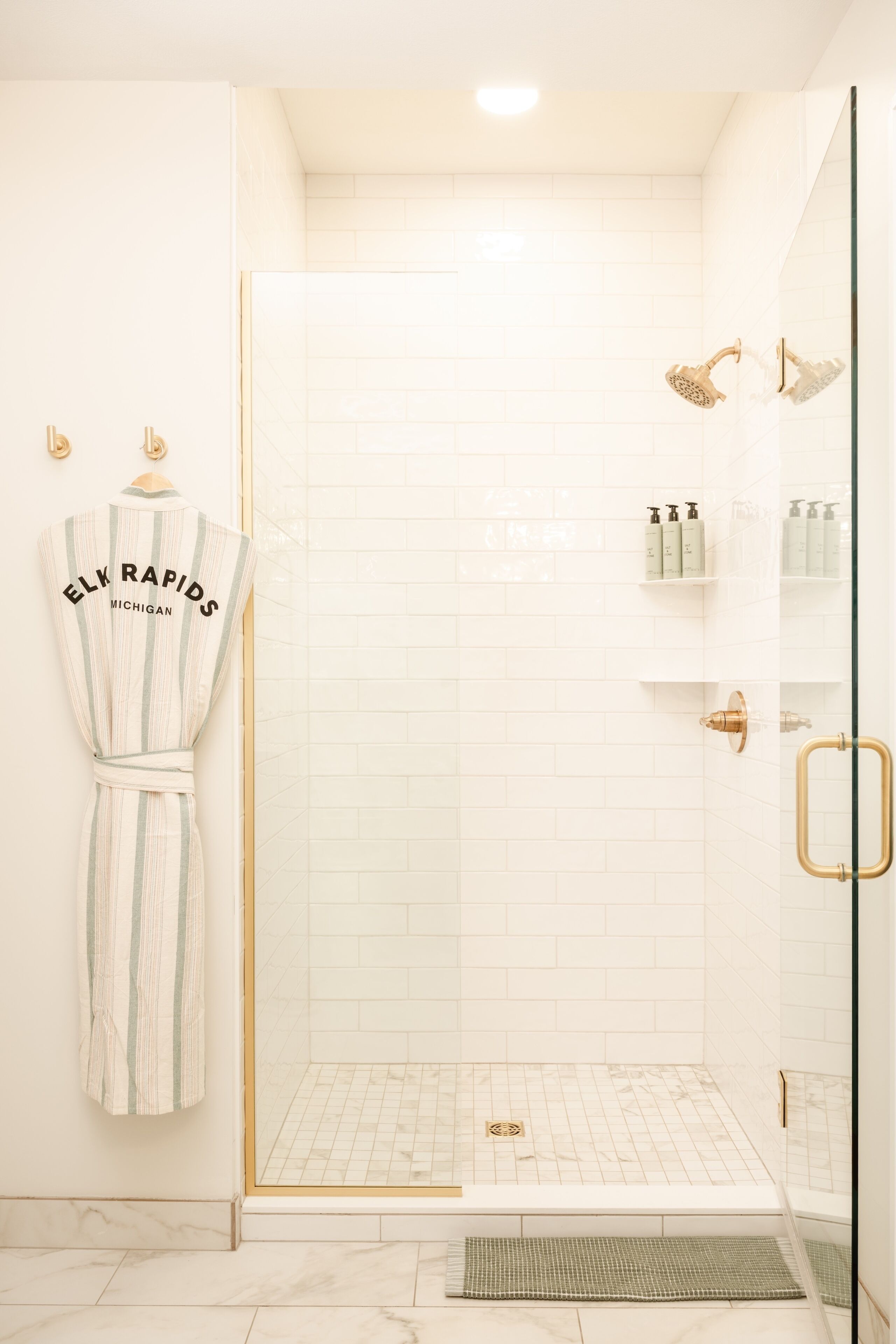 A shower with a glass door, a towel rack with a towel, and toiletries on a shelf.