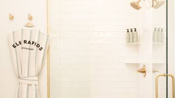 A shower with a glass door, a towel rack with a towel, and toiletries on a shelf.