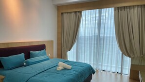 A hotel room with a large bed, a wooden headboard, and a view of the city through sheer curtains. - Spacious 3-bedroom apartment with AC, fitness room in charming Kuching (Kuching)