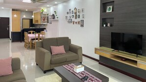 A modern living room with a sofa, TV stand, and a dining area with chairs and a table. - Spacious 3-bedroom apartment with AC, fitness room in charming Kuching (Kuching)