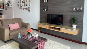 A modern living room with a sofa, coffee table, TV, and decorative items on the wall. - Spacious 3-bedroom apartment with AC, fitness room in charming Kuching (Kuching)