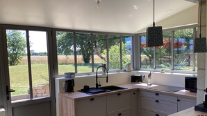 Een moderne keuken met een groot raam, een koffiezetapparaat en een spoelbak.
