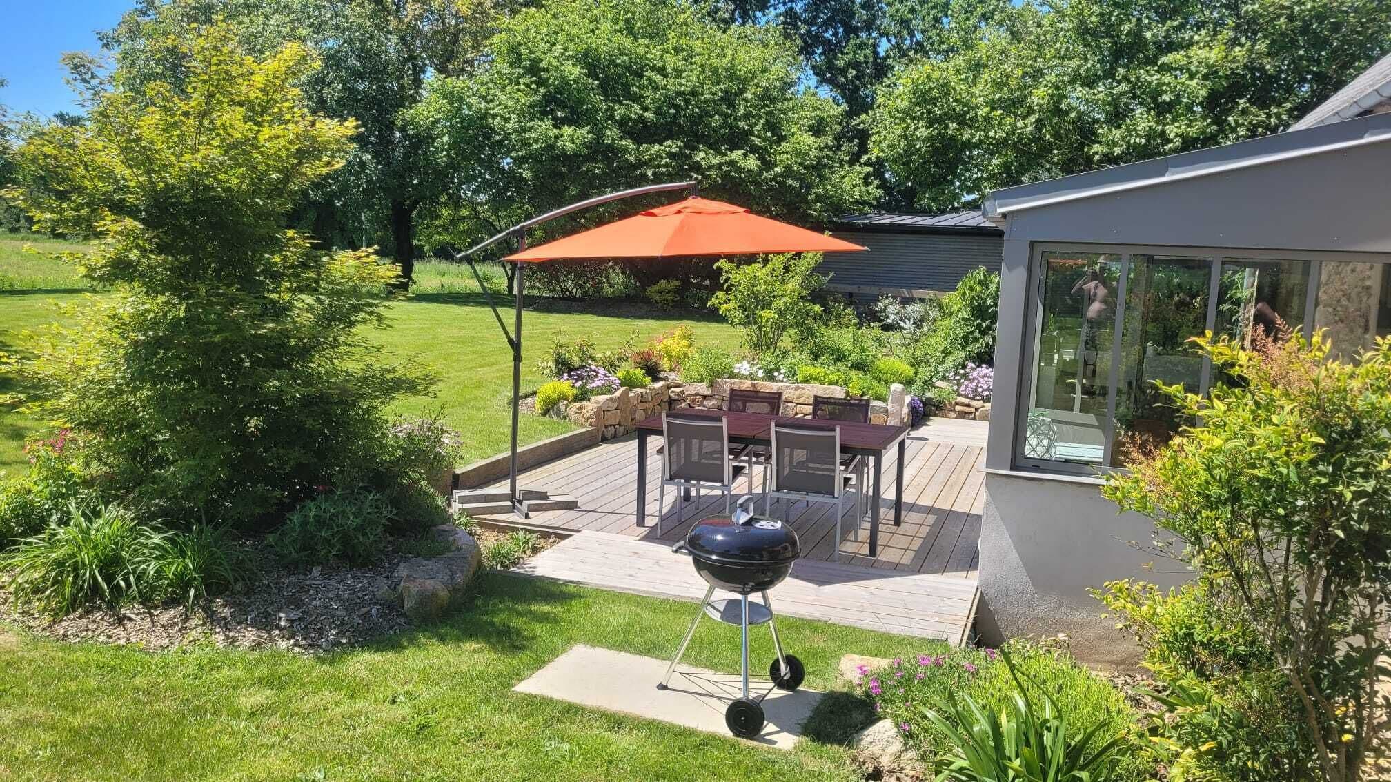 A backyard with a barbecue grill, patio furniture, and a covered seating area.