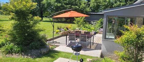 A backyard with a barbecue grill, patio furniture, and a covered seating area.