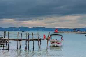 A boat docked at a pier with a chain barrier, calm water, and distant mountains. - Lettry Holiday Hotel (Lingshui)
