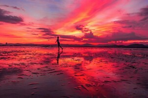 Atardecer sobre una playa con una persona caminando.