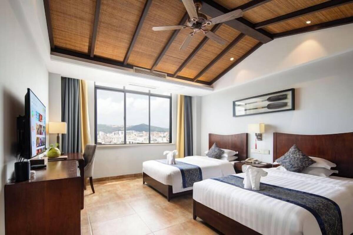 Una habitación de hotel con dos camas, un escritorio, televisión y vistas a la ciudad.
