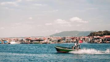 A boat on a body of water with a waterfront area in the background.