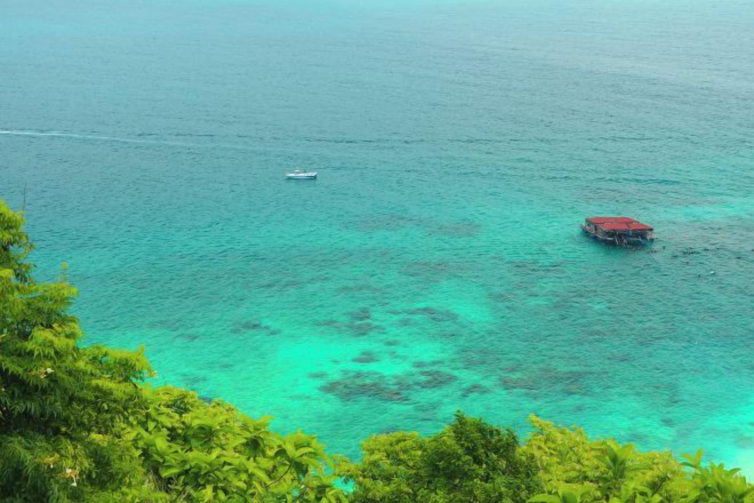 A coastal view with a boat and a red structure in the water.