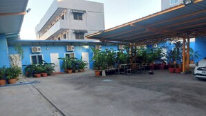 A courtyard with potted plants, a covered seating area, and a white car parked nearby. - NOPPHADON HOTEL (Bangkok)