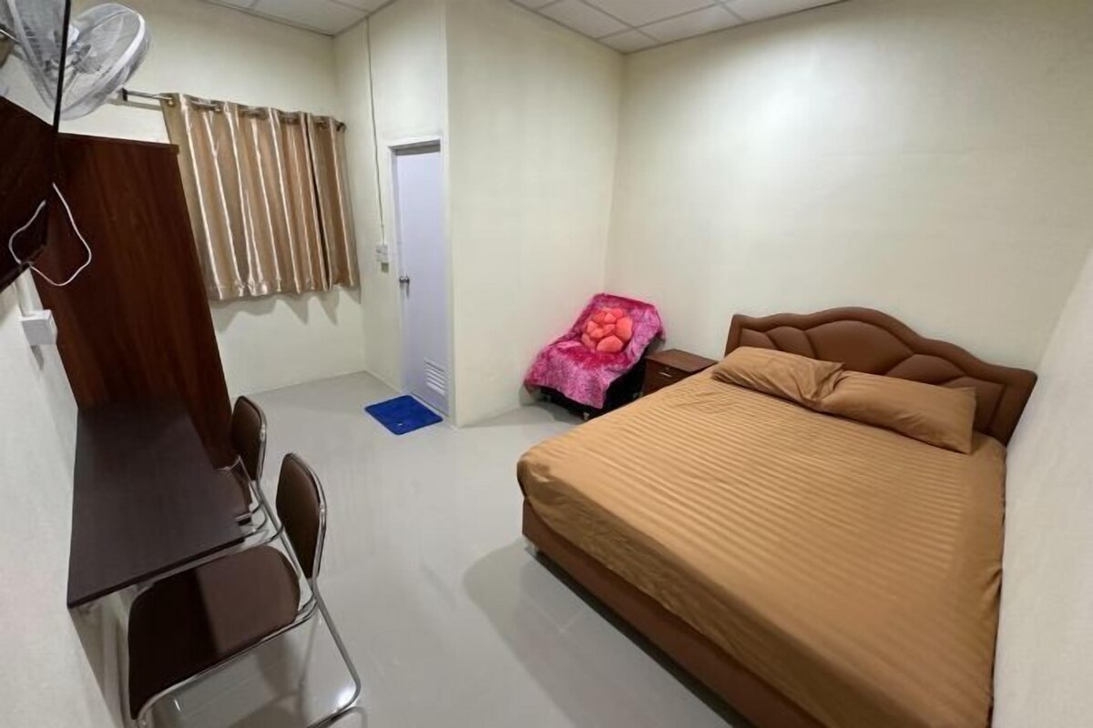 A bedroom with a bed, a desk, and a chair.