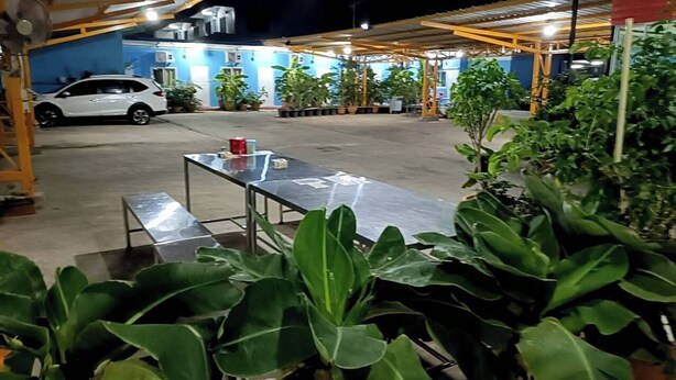 A covered outdoor area with a table and chairs, surrounded by potted plants. - NOPPHADON HOTEL (Bangkok)