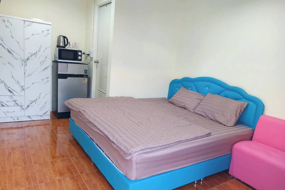 Ein Schlafzimmer mit einem Bett, einem Kleiderschrank, einer Mikrowelle und einem rosa Sessel.