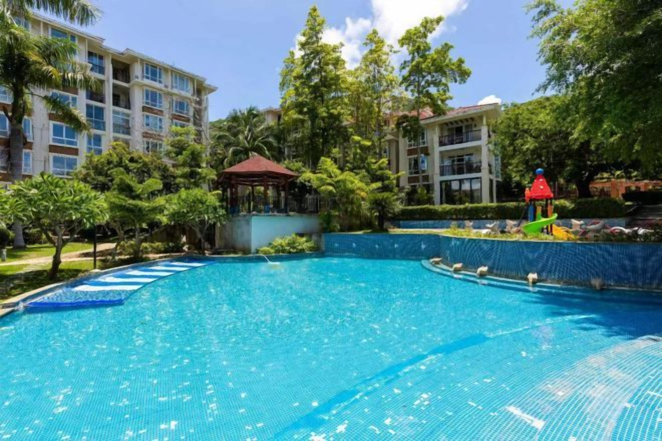 Piscina rodeada por vegetação e edifícios.