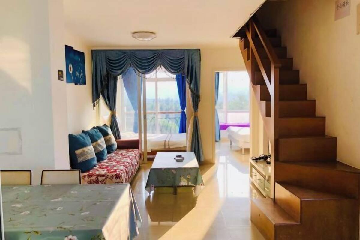 A room with a bed, a sofa, a dining table, and a staircase.