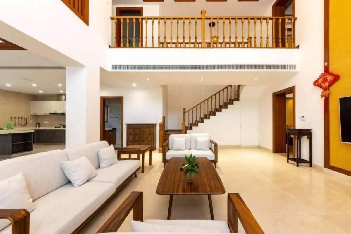A spacious living area with a sofa, coffee table, and a staircase leading to an upper floor.