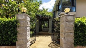 A gated entrance with a wooden pathway leading to a covered area, surrounded by greenery. - Renda Holiday Apartment (Sanya)