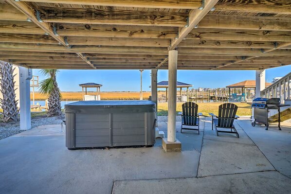 Relax in a hot tub surrounded by a tranquil outdoor space with Adirondack chairs and a barbecue grill.