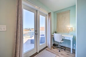 Enjoy a room with a sliding glass door leading to a balcony, a desk, and a wall-mounted lamp.