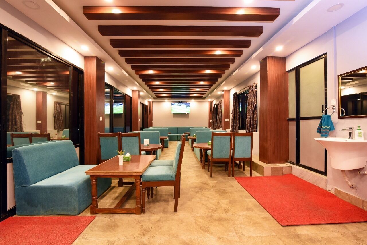 Un vestíbulo de hotel con zonas de estar, un televisor y una recepción.