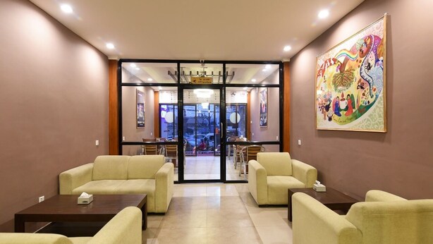 A hotel lobby with a reception desk, seating area, and a large colorful mural on the wall. - Hotel Harmony (Kathmandu)