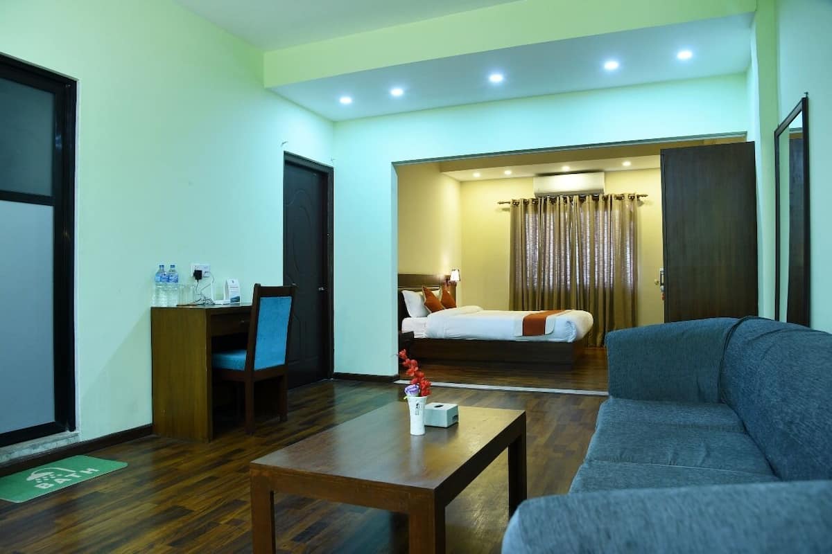 A hotel room with a bed, a desk, a sofa, and a coffee table.
