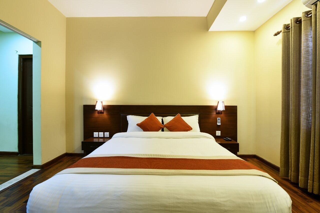 Een hotelkamer met een groot bed, twee nachtkastjes, een spiegel.