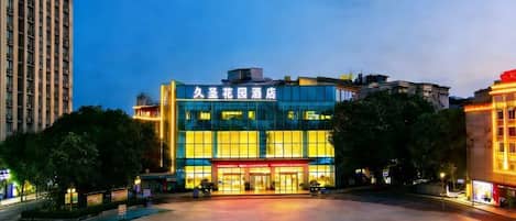 Un edificio moderno con un amplio frente de vidrio, probablemente un hotel o propiedad comercial, con un espacio exterior espacioso al frente.