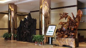 Un hall d’entrée agrémenté d’une sculpture en bois, d’un panneau indicateur avec une flèche et de plantes en pot.