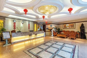 A hotel lobby with a reception desk, seating area, and a chandelier. - Jiusheng Garden Hotel (Luzhou)