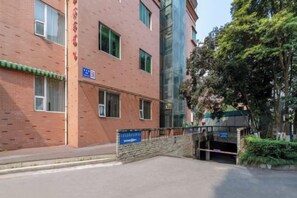 Un bâtiment à la façade en briques, avec une enseigne bleue et une entrée fermée par un portail.