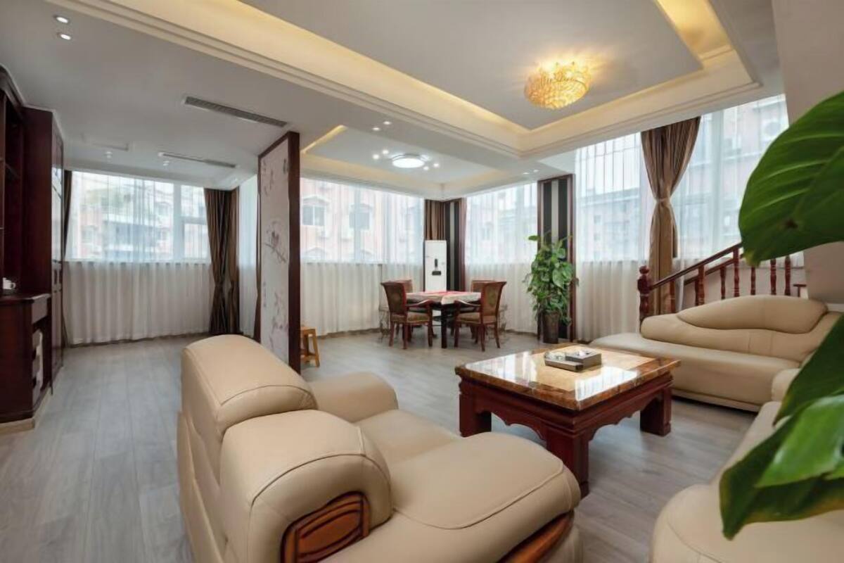 Uma sala de estar ampla com sofá, mesa de centro e área de jantar com cadeiras.