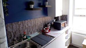 A modern kitchen with a blue accent wall, a stone backsplash, and built-in appliances. - Santoriniapartmentwestkensingtonsleeps3-ensuite-ac (London)