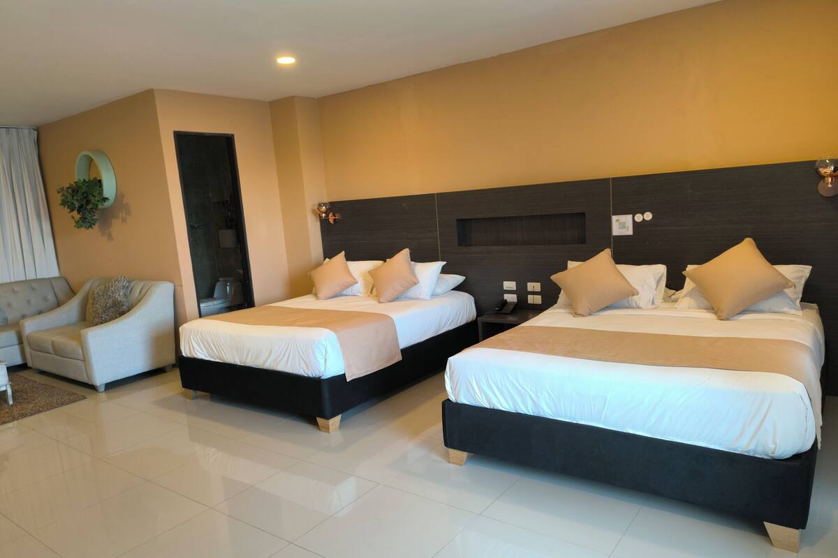 A modern hotel room with two beds, a sofa, and a large mirror.