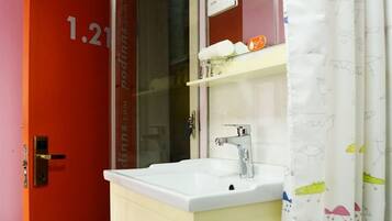 A bathroom with a white sink, a mirror above it, and a shower curtain with a fish pattern.