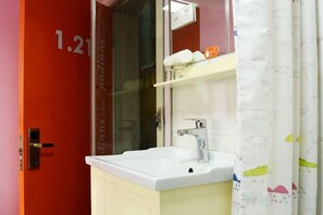 A bathroom with a white sink, a mirror, and a shower curtain with a pattern. - Dingding Hotel (Shanghai New International Expo Center Huaxia East Road Subway Station) (Shanghai)
