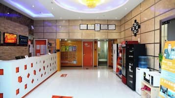 A hotel reception area with a reception desk, a digital display, and a water dispenser.
