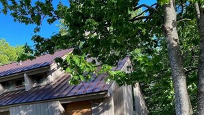Une cabane rustique avec un toit en métal, des murs en bois et un petit porche.