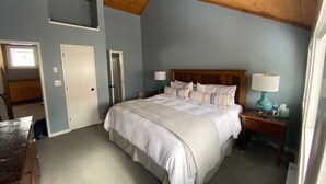 Une chambre à coucher avec un lit, des tables de chevet, une lampe et une porte.