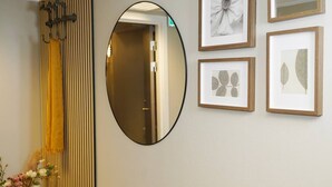 Ένας διάδρομος με έναν καθρέφτη, κορνιζωμένα σχέδια με θέμα τη βοτανική και μια κάθετη ραβδωτή διακοσμητική επιφάνεια.