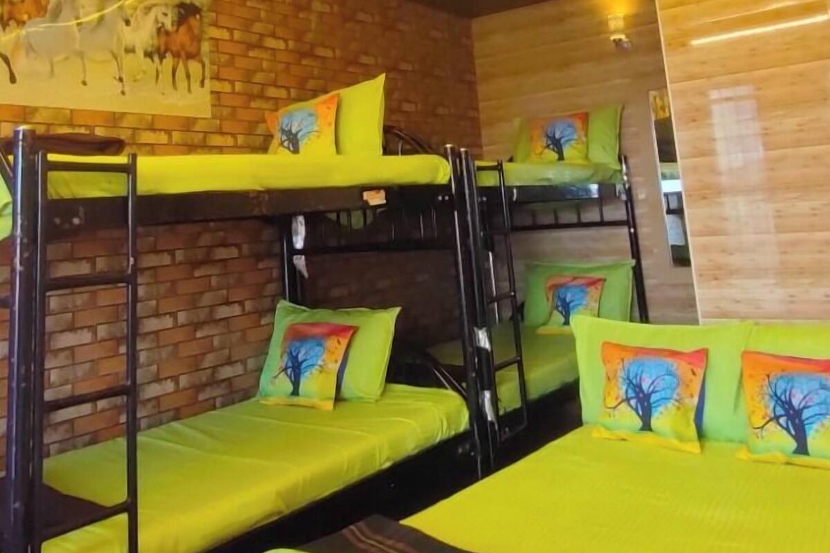 Ein Zimmer mit Etagenbetten, Holzboden und einer Backsteinwand.