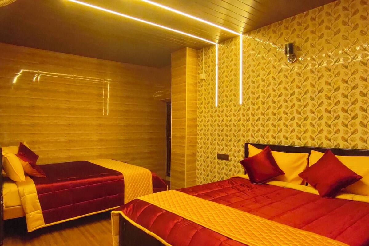 Ein Hotelzimmer mit einer Holzwand, einem Bett mit roter und gelber Bettwäsche sowie einer kleinen Sitzecke.