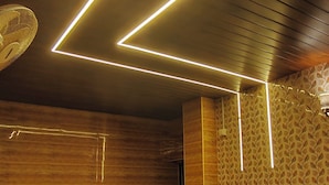 Une chambre moderne avec deux lits, un lambris en bois et un éclairage au plafond aux motifs géométriques.